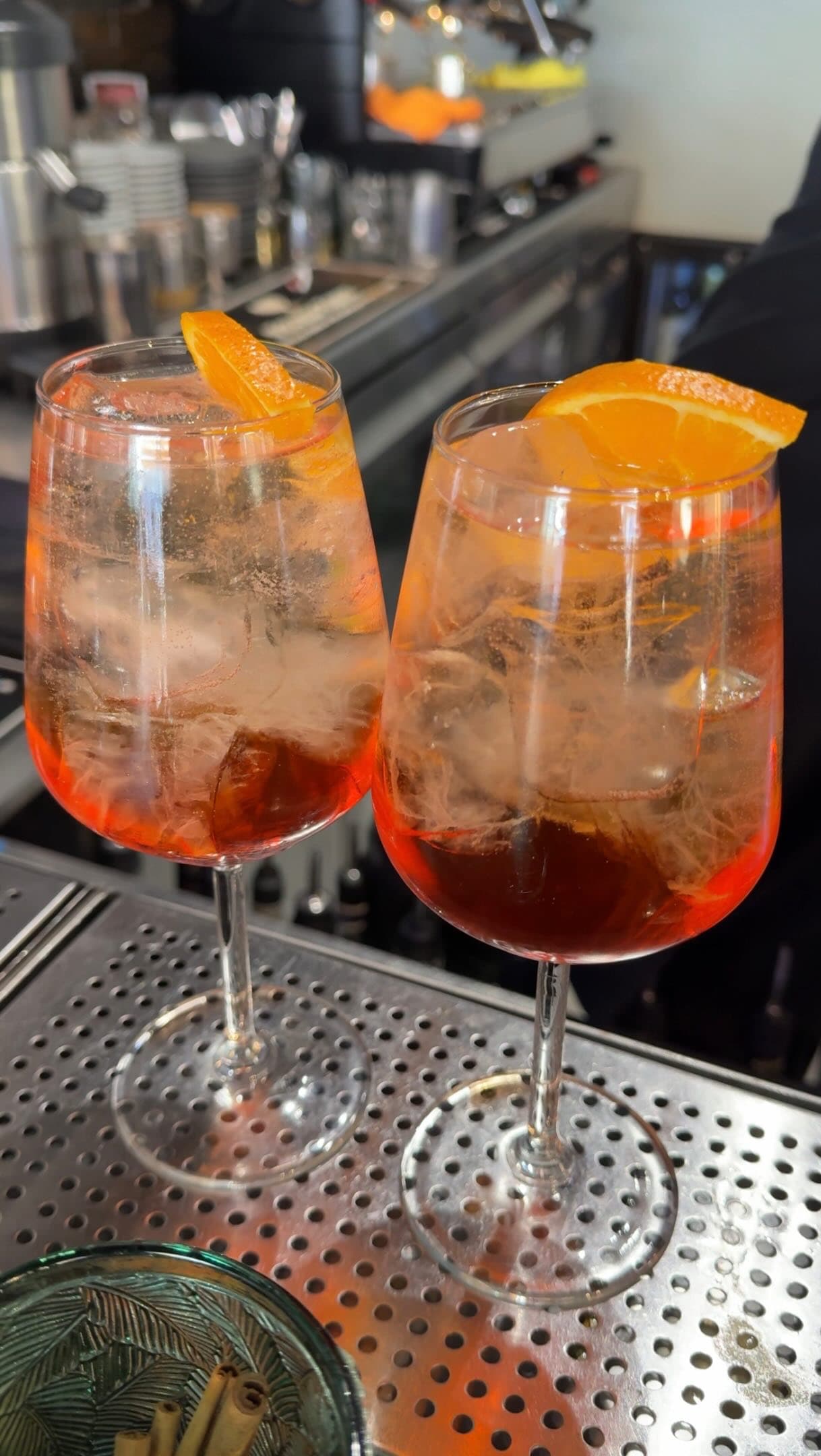 Two Aperol spritzes on the steel bar top